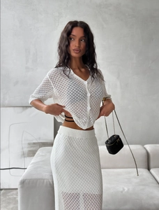 Detail of white hollow crochet knit cardigan and matching skirt set with textured patterns
