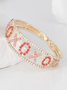 Detailed macro view of gold-plated cuff featuring pink XOXO rhinestone patterns