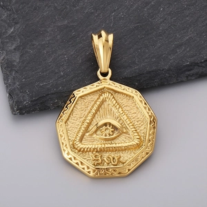Macro detail of golden octagonal Eye of Providence pendant on a dark grey stone surface