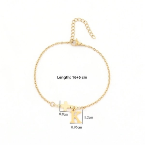 Detail einer Goldkette Armband mit Kreuzanhänger und Buchstabe K auf weißem Hintergrund