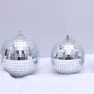 Silver disco mirror balls in two sizes with hanging loops on a white plush surface