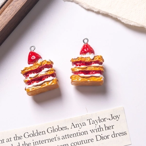 Detail showing two miniature strawberry Napoleon cake pendants with metal hanging rings