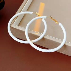 Detailed view of large white leather wrapped hoop earrings with gold metallic clasps