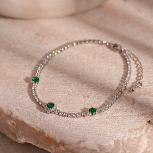 Macro view of silver-tone tennis bracelet with green emerald cubic zirconia on stone base