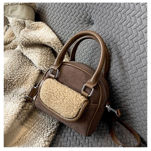 Detail of brown suede tote bag with cream teddy fur pocket and dual leather handles