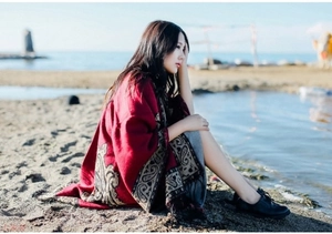 Close-up of a warm red cashmere shawl with intricate paisley patterns on a sunny beach