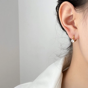 Close-up of gold pear cut drop earrings with clear zircon pendant on a model's ear