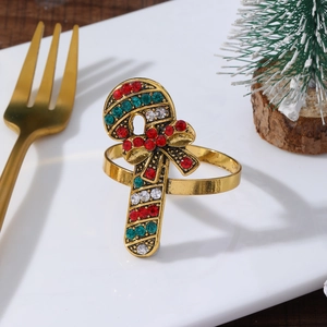 Detail of candy cane napkin ring with red and green crystals on a white ceramic plate