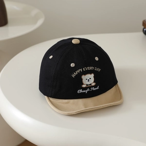 Détail d'une casquette bébé avec visière jaune et broderie ours sur coton noir de qualité