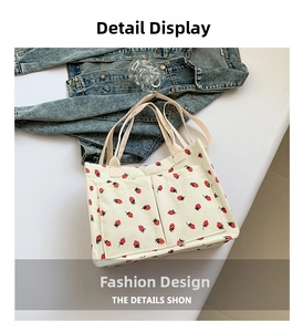 Detail view of corduroy tote bag with red strawberry pattern and functional front pockets