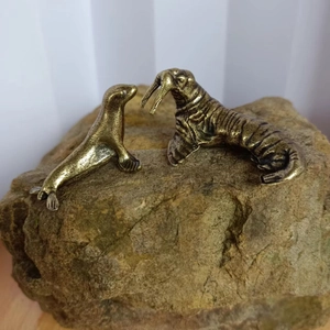 Detailed close-up of vintage solid brass walrus and sea lion metal figurines on a rock