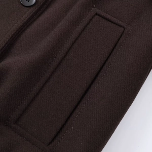 Détail d'un manteau en laine marron foncé avec tissu texturé et coutures apparentes