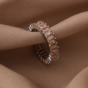 Macro shot of silver ring with orange-pink rectangular zircon on brown silk background