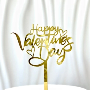 Macro shot of gold acrylic Happy Valentine's Day cake topper with hollow heart designs