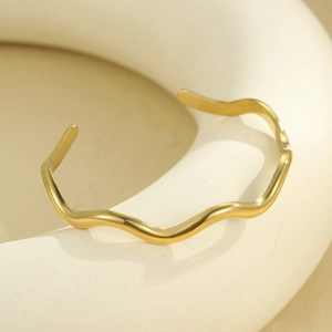 Minimalist gold wave open bangle with a high-polish finish in a modern geometric style