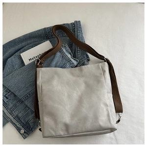 Detail of light gray tote bag featuring brown adjustable strap and side pocket design