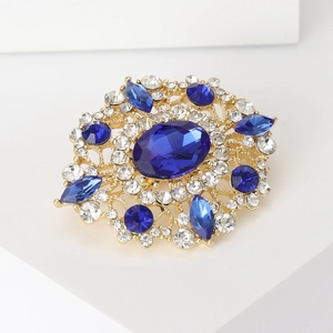 Detail of vintage oval blue rhinestone brooch with a floral gold-tone metal setting