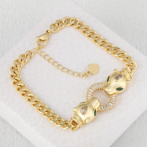 Golden cheetah head bracelet with green zircon eyes and pavé stones on marble background