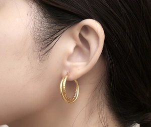 Macro detail of gold double hoop earrings with one smooth and one twisted rope texture