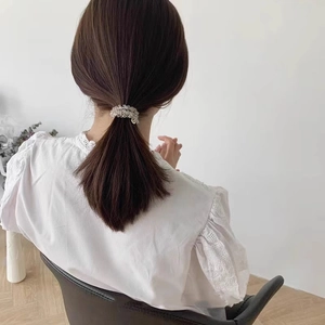 Detail of a ponytail tied with a crystal beaded hair tie showing transparent beads