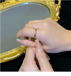 Close-up of a faceted gold-plated titanium ring on a finger with a luxury mirror background