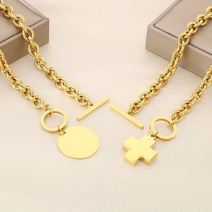 Flat lay of gold OT buckle necklaces with round and cross pendants on beige fabric