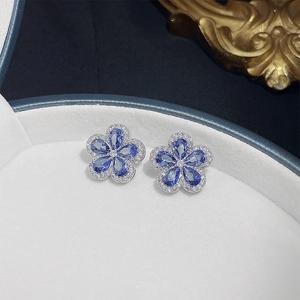Macro shot of silver flower earrings featuring blue teardrop stones and white zircon trim