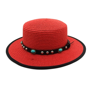 Close-up of red straw boater hat with turquoise stones and metallic stud detailing
