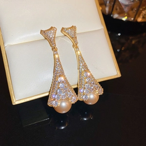 Macro shot of gold tassel earrings with sparkling crystals and champagne pearls in a jewelry box