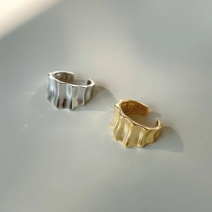 Detail of wide wavy textured open rings in polished gold and silver finishes