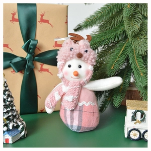 Detail of pink snowman plush ornament with reindeer antlers in a cozy festive setting