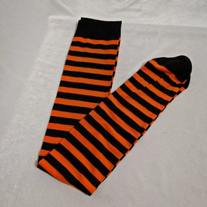 Detail of orange and black striped over-knee high socks laid on a white fabric surface
