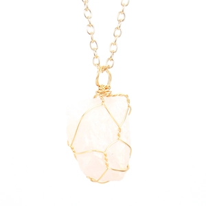 Detail of handmade wire-wrapped rose quartz pendant on a delicate gold chain necklace