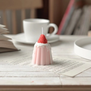 Pink strawberry cannelé pudding candle on a warm cozy desk with aesthetic book decor