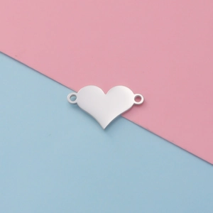 Close-up of a polished stainless steel heart connector charm on a pastel background