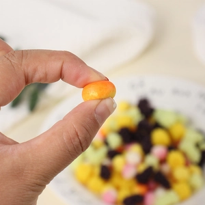 Mini juguete naranja antiestrés de TPR en la mano que muestra su tamaño y su textura