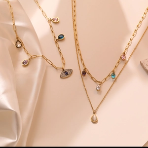 Gold evil eye necklace with layered zircon waterdrop pendants on silk background