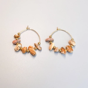 Detail of bohemian gold hoop earrings featuring irregular natural stones and metal beads
