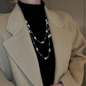 Close-up of layered baroque pearl necklace draped over a black turtleneck sweater