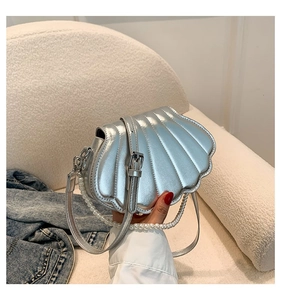 Detailaufnahme der silbernen Muscheltasche mit elegantem Perlenhandgriff und Glanz