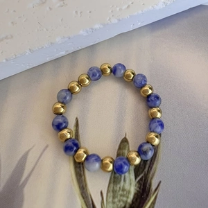 Adjustable elastic beaded ring featuring 3mm blue marble stone and golden metal beads