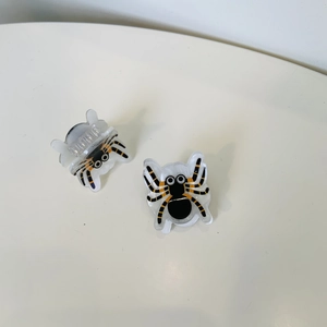 Detail of spider-shaped acrylic hair claws with black and yellow patterns in a set of two