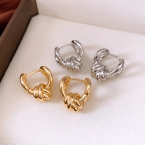 Macro detail of twisted knot earrings in polished gold and silver finishes