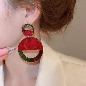 Macro view of geometric resin drop earrings featuring retro marble patterns on ear