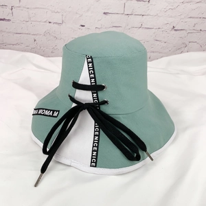 Détail du chapeau bob en toile verte avec lacets noirs et broderies de lettres