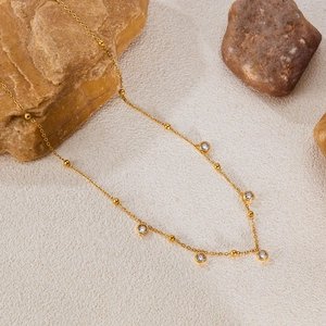 Detail of a minimalist gold-plated necklace with clear cubic zirconia stones on stones