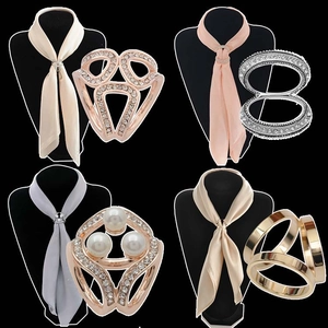 Detail view of four elegant silk scarf clips with rhinestones and pearls on satin scarves