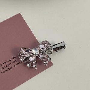 Close-up of pink rhinestone bow hair clip with silver alloy base on a gift card