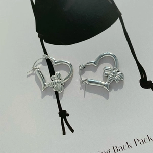 Minimalist silver heart bee earrings with polished finish on a modern magazine background