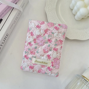 Detailed view of pink floral quilted fabric storage pouch with rabbit pattern and brand tag